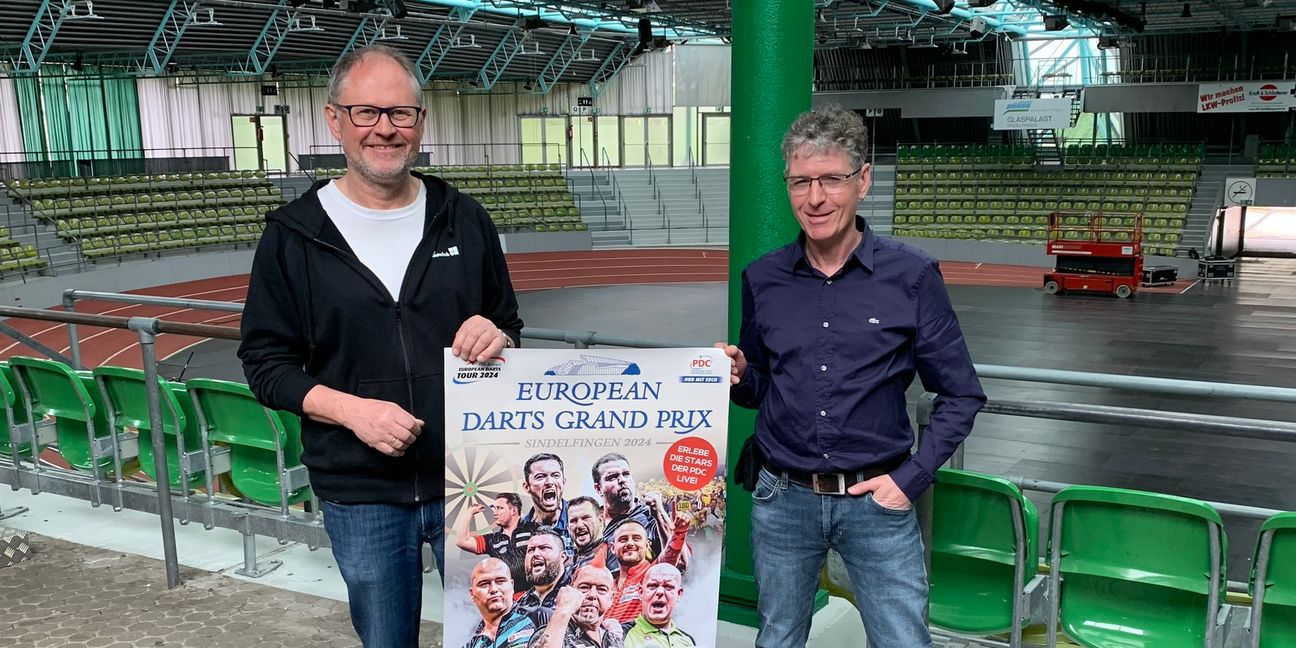 Uwe Dieterich (links) und Claus Regelmann präsentieren das Plakat des European Darts Grand Prix. Am Wochenende platzt der Glaspalast aus allen Nähten. Bild: Holzapfel